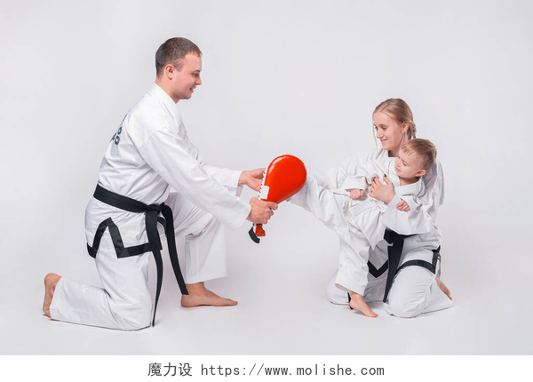 白色背景墙练习跆拳道的小孩年轻的家庭和他们的小男孩在白人背景下练习武术